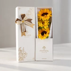 Box blanco con tres girasoles amarillos naturales y follaje verde